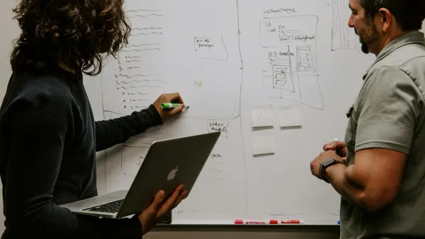 Two people mapping out a focused marketing plan on a whiteboard — planning the messages, channels and buyer stages that make up the 3-3-3 rule