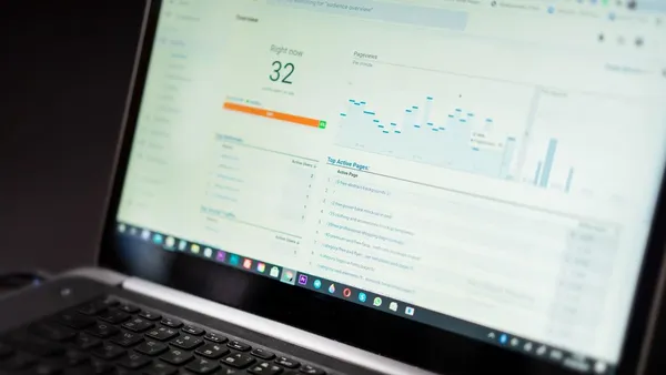 A laptop screen showing a real-time web analytics dashboard with active users and traffic charts — done-for-you marketing for a SaaS product