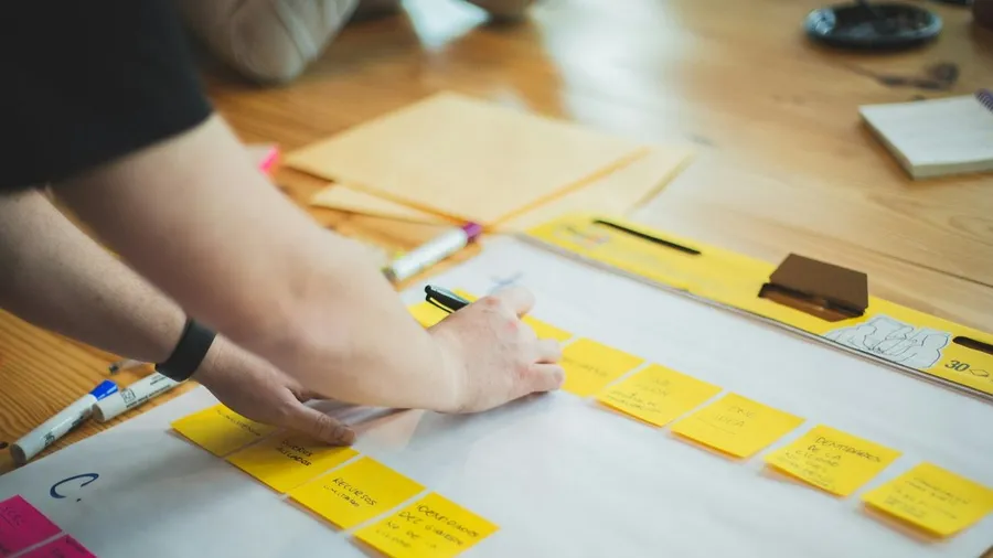A marketer mapping out a strategy with sticky notes and markers on a large sheet of paper, capturing the strategic planning a fractional CMO is hired to deliver
