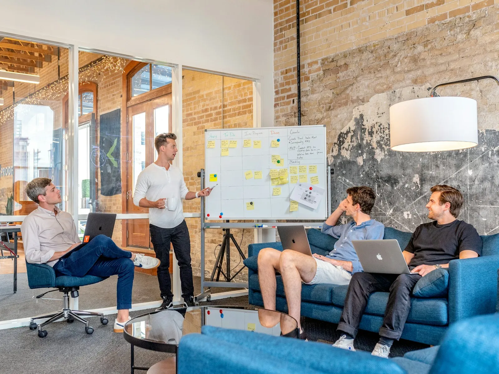 A marketing team collaborating at a whiteboard with laptops — an outsourced marketing function delivering for a client
