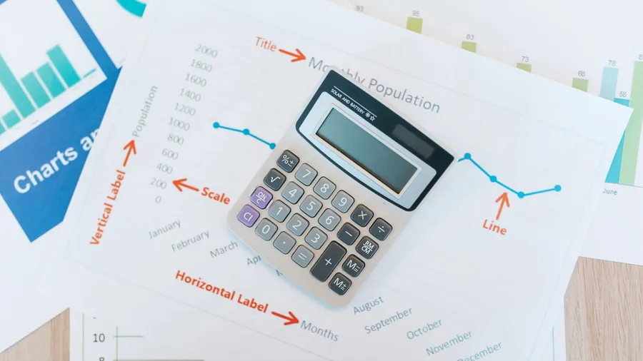 A founder working through revenue growth and profit margin figures with a calculator and printed graphs, the two numbers behind the Rule of 40