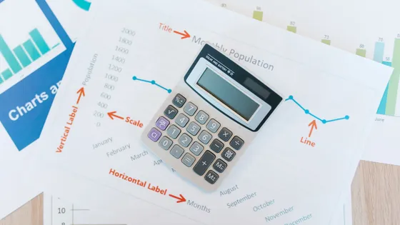 A founder working through revenue growth and profit margin figures with a calculator and printed graphs, the two numbers behind the Rule of 40