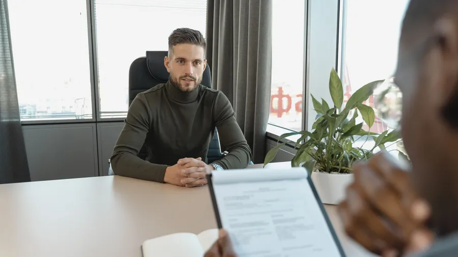 Startup founder weighing a fractional CMO against a done-for-you managed marketing service that handles both strategy and execution, at a desk with a laptop