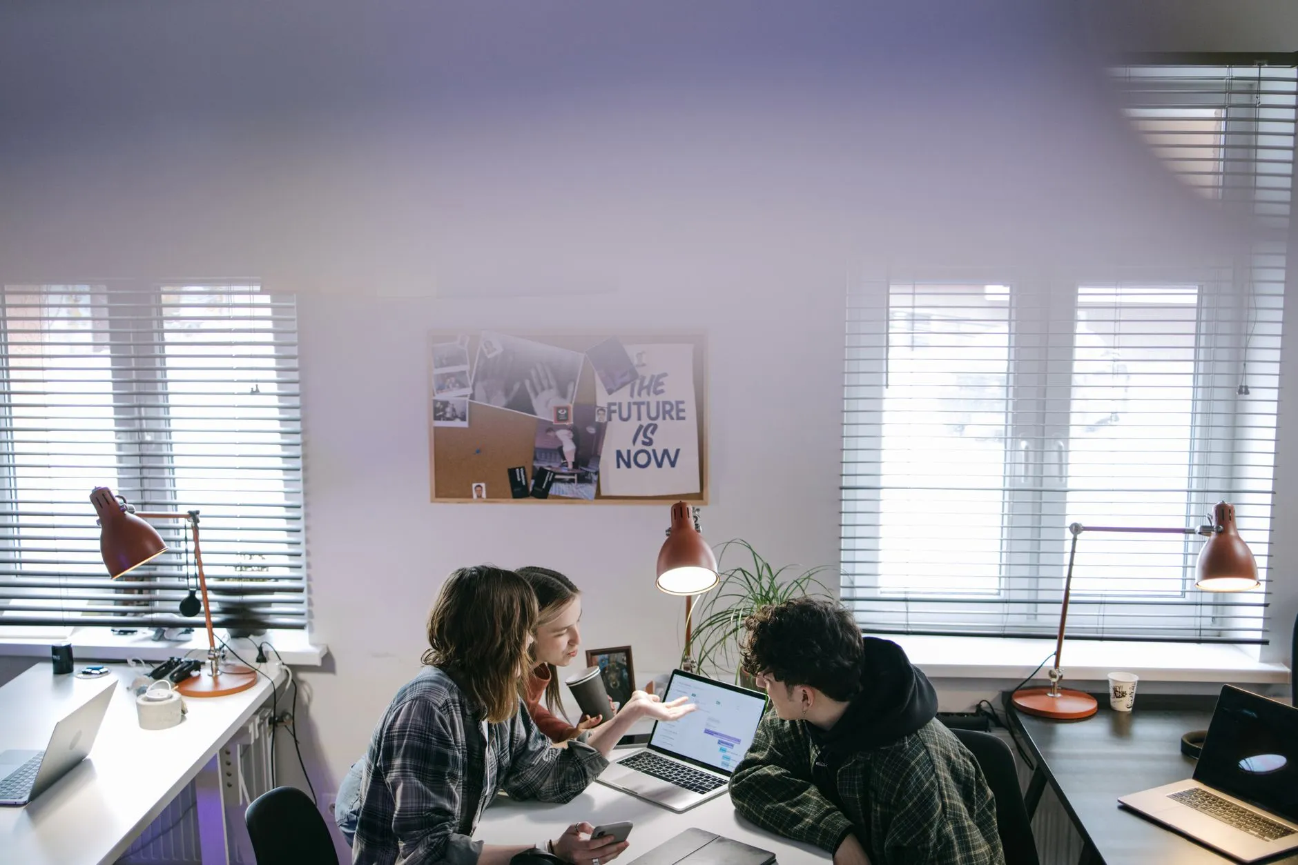 Small team collaborating around laptops in a bright modern office, the kind of dedicated team a good agency provides