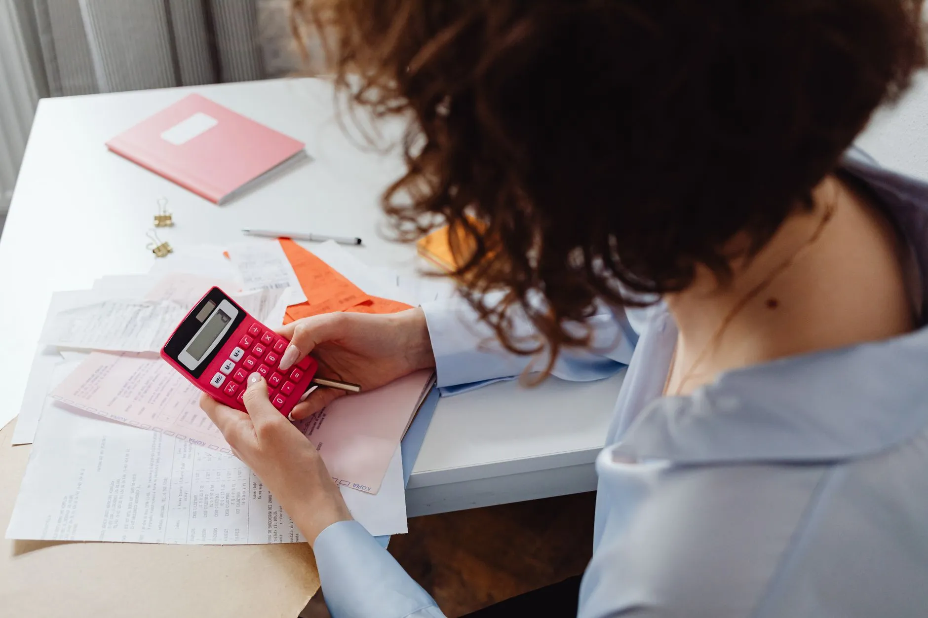 Business owner reviewing expenses and financial planning at a desk, working through the real cost of marketing outsourcing options